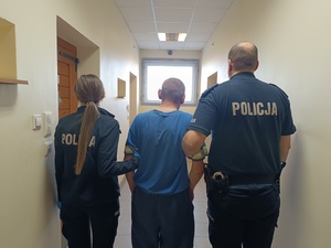 na zdjęciu widnieje dwóch policjantów a w środku włamywacz
