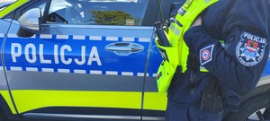 widzimy część postaci policjanta, a w tle policyjny radiowóz.