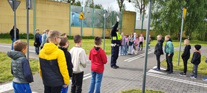 widzimy policjanta ruchu drogowego kierującego ruchem drogowym na miasteczku ruchu drogowego oraz dzieci.