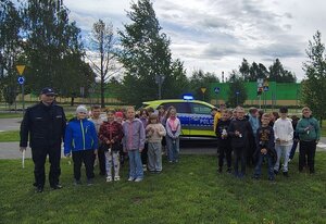 widzimy zdjęcie grupowe dzieci wraz z policjantami na tle policyjnego radiowozu.