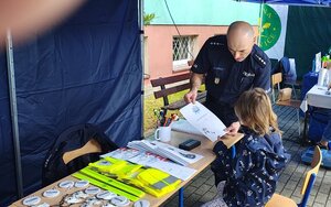 widzimy policjanta z odwiedzającymi stanowisko dziećmi.
