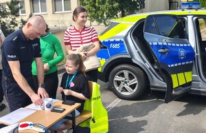 widzimy policjanta z odwiedzającymi stanowisko dziećmi.