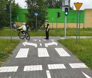 widzimy uczestnika jadącego rowerem na miasteczku ruchu drogowego.