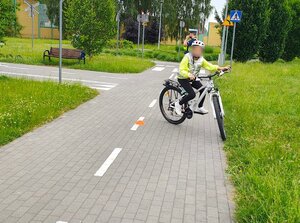 widzimy uczestnika jadącego rowerem na miasteczku ruchu drogowego.