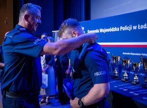 komendant zakłada medal policjantowi.