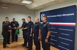 widzimy gratulacje składane policjantom przez mężczyznę w garniturze.