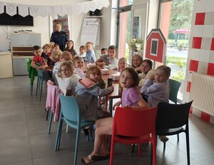 widzimy policjantkę prowadzącą zajęcia oraz dzieci będące w sali.