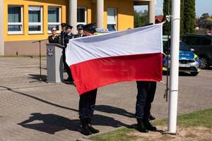 widzimy jak policjanci zakładają flagę na maszt.