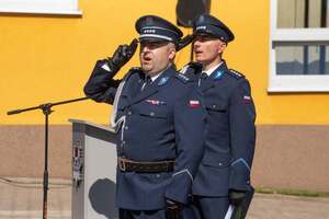 widzimy policjantów oddających honor podczas śpiewu.