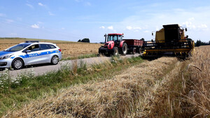 na zdjęciu widnieje kombajn zbożowy oraz traktor i radiowóz policyjny