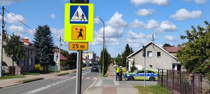 na zdjęciu widnieją policjanci w rejonie przejścia dla pieszych i radiowóz policyjny
