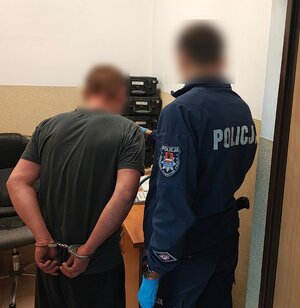 widzimy policjanta z zatrzymanym w pomiesczeniu.