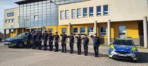widzimy policjantów przed budynkiem komendy przy radiowozach na tle komendy.